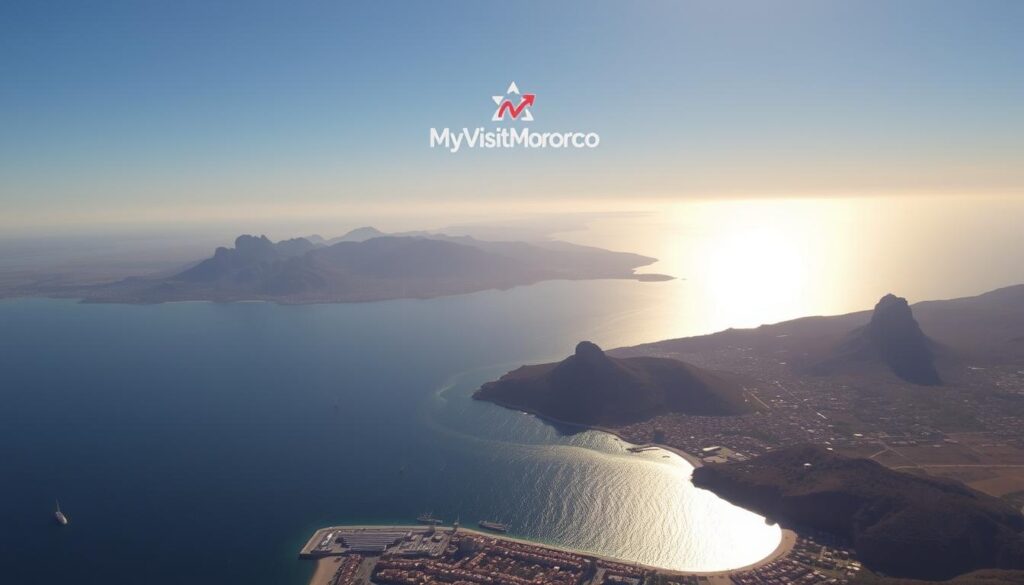 A breathtaking aerial view of the Strait of Gibraltar, the narrow waterway connecting the Mediterranean Sea and the Atlantic Ocean. In the foreground, the vibrant city of Malaga, Spain, nestled along the Andalusian coast. Across the shimmering waters, the rugged peaks of the Rif Mountains in Morocco rise majestically, hinting at the rich cultural tapestry that awaits visitors. Warm, golden sunlight bathes the scene, capturing the unique bond between these two regions. In the distance, the iconic "MyVisitMorocco" logo hovers, symbolizing the seamless connectivity that allows travelers to explore the captivating landscapes and ancient traditions of this remarkable corner of the world.